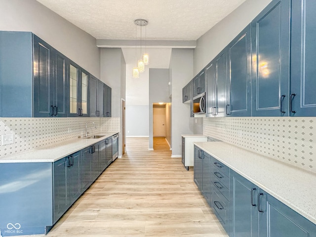 9362 Helmsdale Dr, Indianapolis, IN 46256 - kitchen featuring a sink, light wood finished floors, stainless steel microwave, backsplash, and blue cabinetry