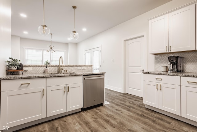 kitchen featuring backsplash, stainless steel dishwasher, wood finished floors, a sink, and white cabinets