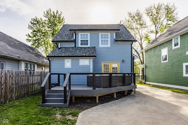 back of property with french doors, fence, a wooden deck, and a shingled roof