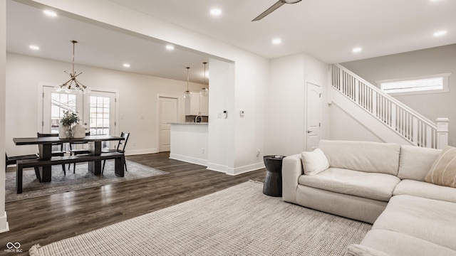 living room featuring recessed lighting, baseboards, dark wood finished floors, and stairs