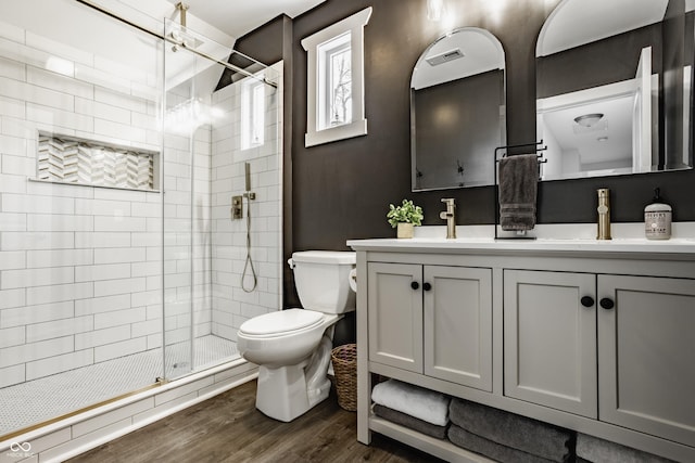 bathroom featuring visible vents, a shower stall, wood finished floors, vanity, and toilet