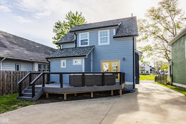 back of house featuring roof with shingles, fence, french doors, and a deck