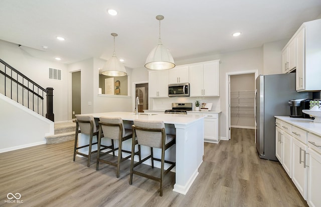 827 Allandale Ave, Westfield, IN 46074 - kitchen with stainless steel appliances, light countertops, light wood-type flooring, white cabinetry, and a kitchen breakfast bar