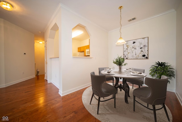 dining room with baseboards, ornamental molding, and wood finished floors
