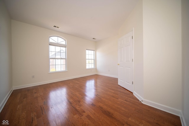 spare room featuring baseboards, visible vents, and wood finished floors