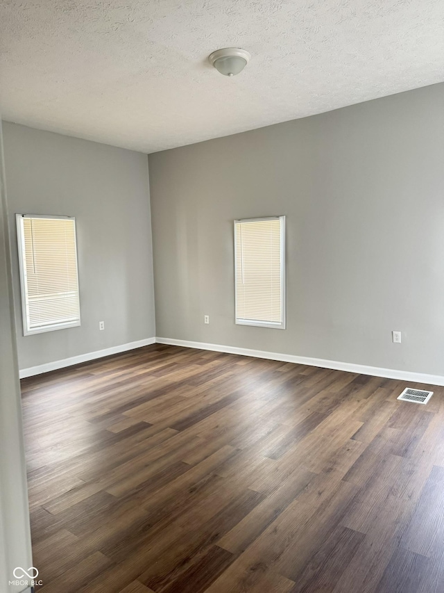 3502 N Illinois St, Indianapolis, IN 46208 - spare room featuring dark wood-type flooring, visible vents, baseboards, and a textured ceiling