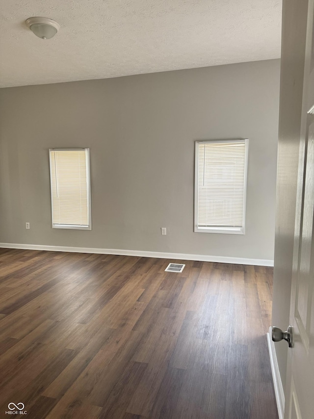 3502 N Illinois St, Indianapolis, IN 46208 - empty room with dark wood-style flooring, visible vents, baseboards, and a textured ceiling