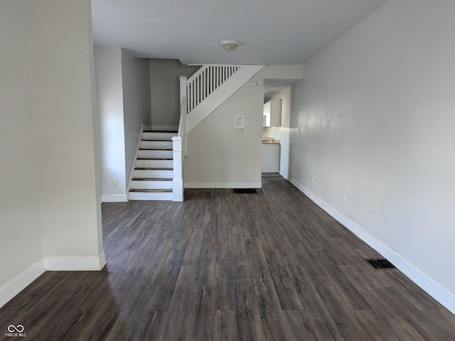 unfurnished living room featuring visible vents, baseboards, stairs, and dark wood finished floors