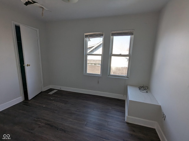 spare room featuring baseboards and dark wood finished floors