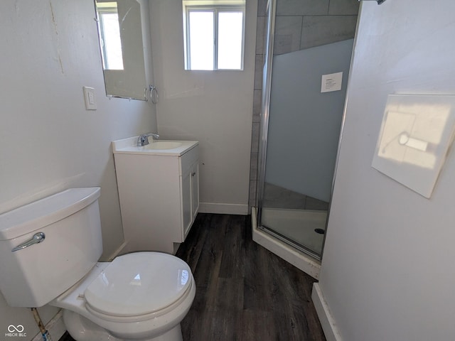 bathroom featuring a shower stall, vanity, toilet, wood finished floors, and baseboards