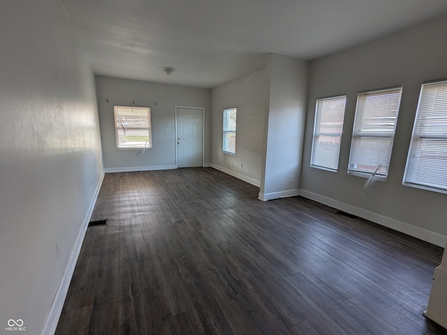 unfurnished room featuring dark wood-style flooring, baseboards, and visible vents