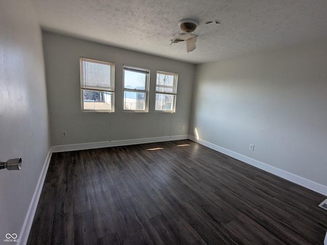 empty room featuring baseboards, dark wood-type flooring, a textured ceiling, and a ceiling fan