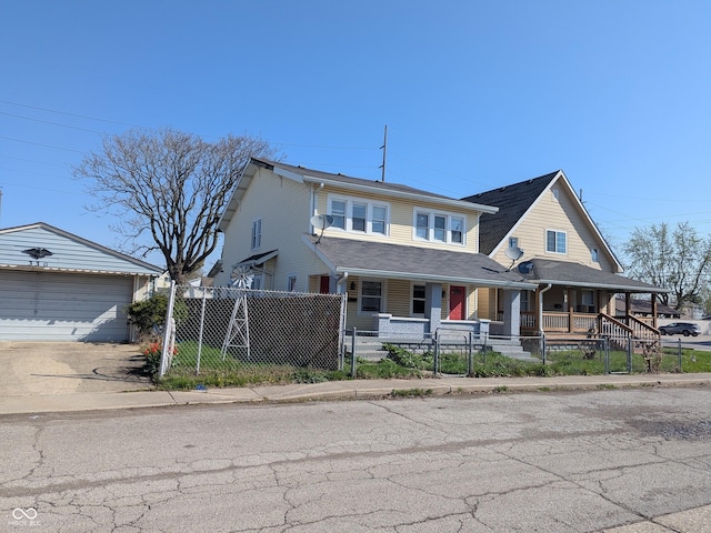 view of front facade featuring concrete driveway, a fenced front yard, a porch, an outbuilding, and a garage
