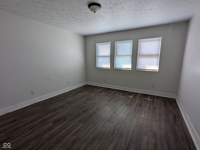 spare room featuring dark wood-type flooring, baseboards, and a textured ceiling
