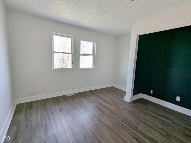 408 E Beecher St, Indianapolis, IN 46225 - spare room featuring dark wood-type flooring, a textured ceiling, and baseboards