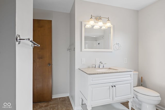 bathroom with toilet, vanity, and baseboards