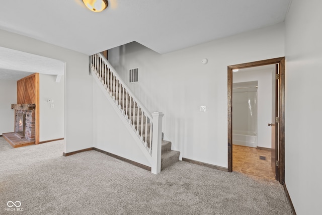 stairway featuring carpet flooring, baseboards, and a brick fireplace