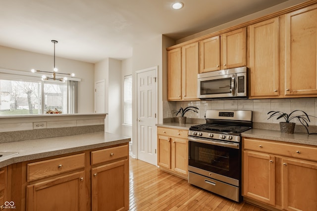 12561 Gladecrest Dr, Carmel, IN 46033 - kitchen with appliances with stainless steel finishes, a chandelier, tasteful backsplash, light wood-style flooring, and recessed lighting