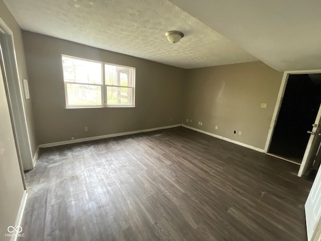 unfurnished room with baseboards, a textured ceiling, and dark wood finished floors