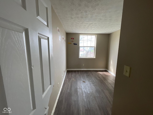empty room featuring baseboards, wood finished floors, and a textured ceiling
