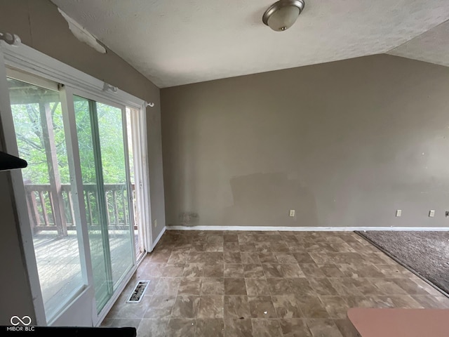 unfurnished room featuring lofted ceiling, visible vents, and baseboards