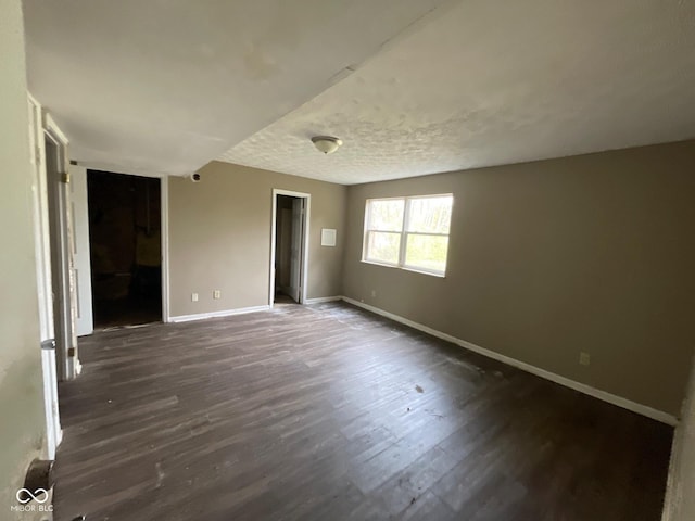 unfurnished room with baseboards and dark wood-style flooring
