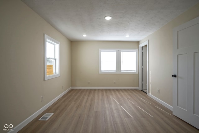 empty room featuring baseboards, plenty of natural light, light wood-style flooring, and visible vents