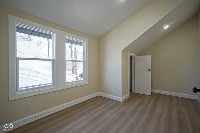 bonus room with wood finished floors, baseboards, and lofted ceiling