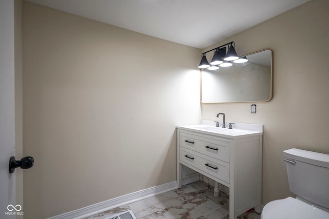 half bath featuring vanity, baseboards, toilet, and marble finish floor
