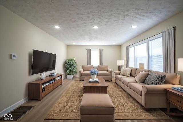 living area with a textured ceiling, visible vents, baseboards, recessed lighting, and light wood-style flooring