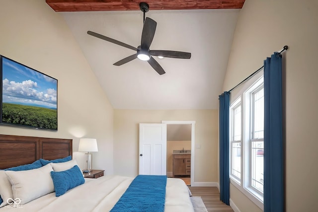 bedroom featuring multiple windows, vaulted ceiling, light wood finished floors, and connected bathroom