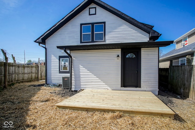 rear view of property featuring central AC, a wooden deck, and a fenced backyard