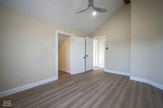 interior space with baseboards, a ceiling fan, wood finished floors, and high vaulted ceiling