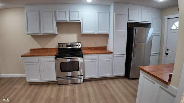 kitchen with white cabinetry, wood counters, appliances with stainless steel finishes, and light wood finished floors