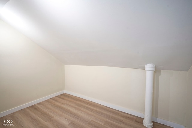 bonus room with light wood-style floors, baseboards, and vaulted ceiling