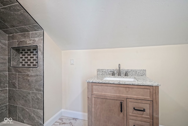 bathroom featuring baseboards, tiled shower, marble finish floor, and vanity