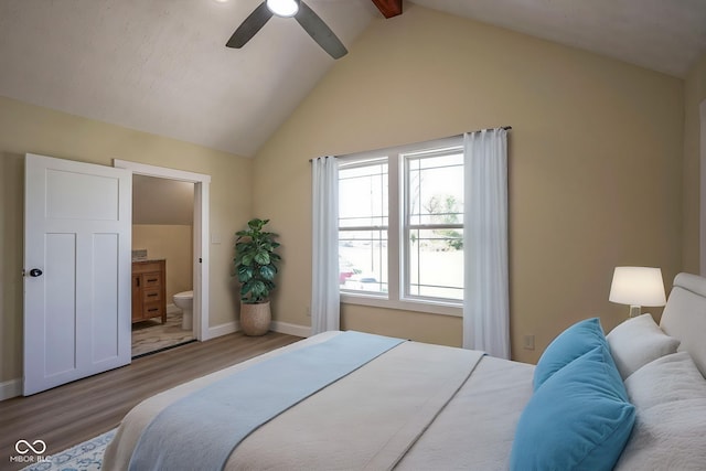 bedroom with connected bathroom, lofted ceiling with beams, a ceiling fan, baseboards, and wood finished floors