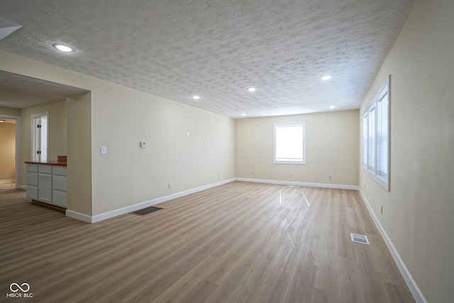 interior space with visible vents, a textured ceiling, and wood finished floors
