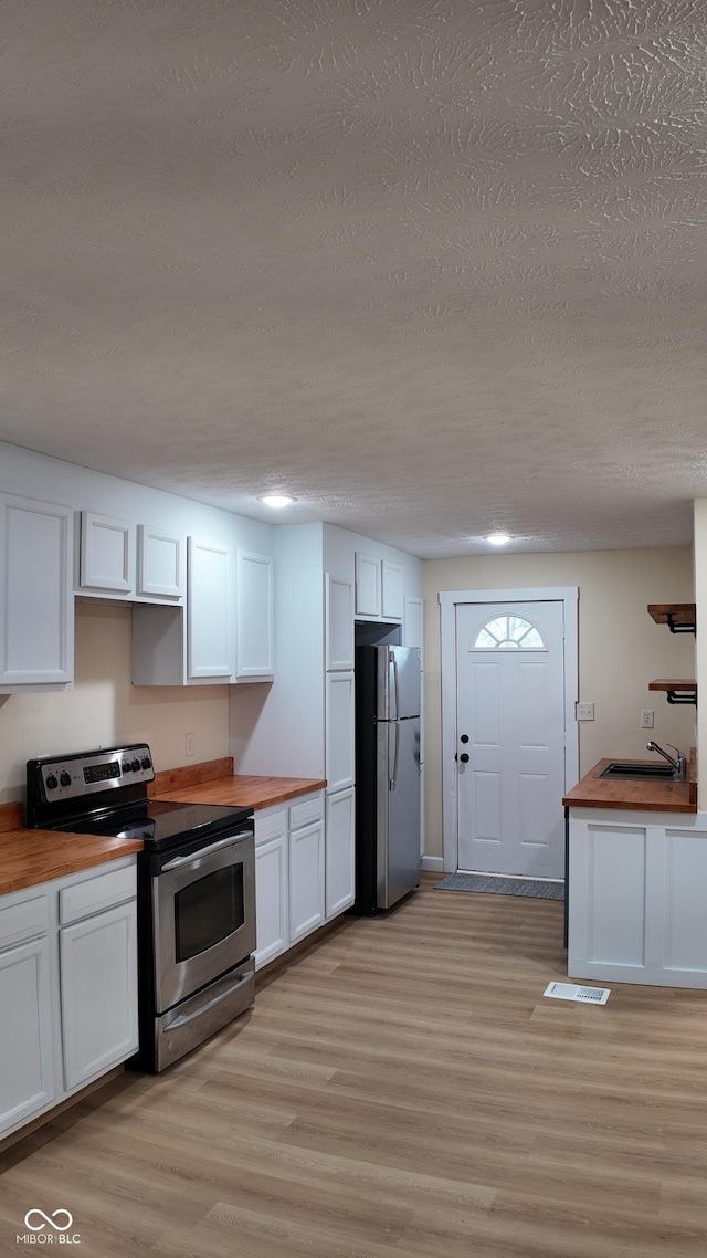 kitchen featuring a sink, white cabinetry, appliances with stainless steel finishes, and butcher block counters