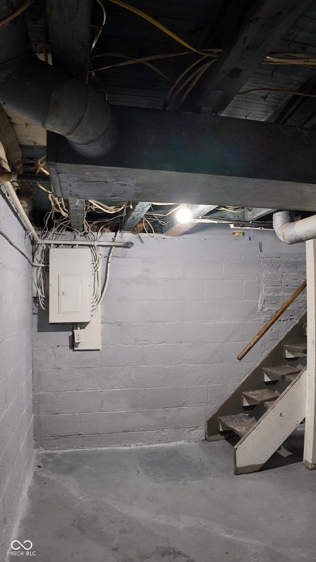 unfinished below grade area featuring electric panel and stairway