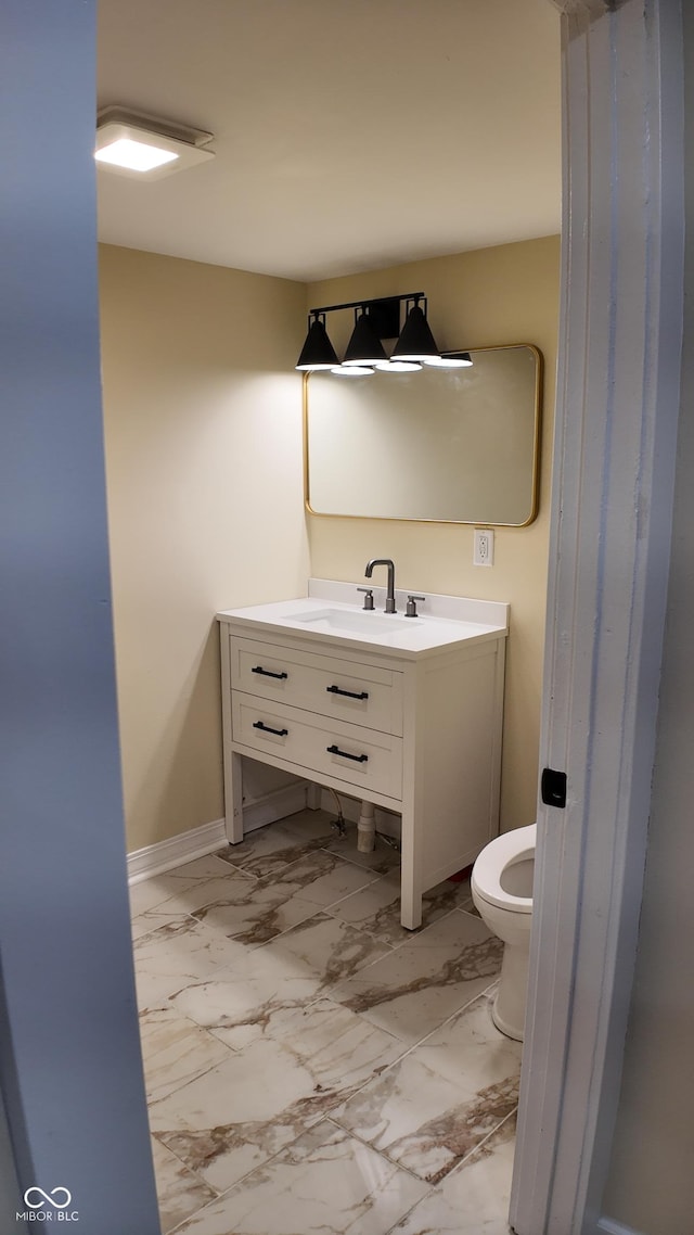 half bath with vanity, marble finish floor, baseboards, and toilet