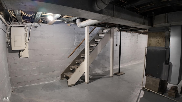unfinished below grade area featuring heating unit, stairway, and electric panel