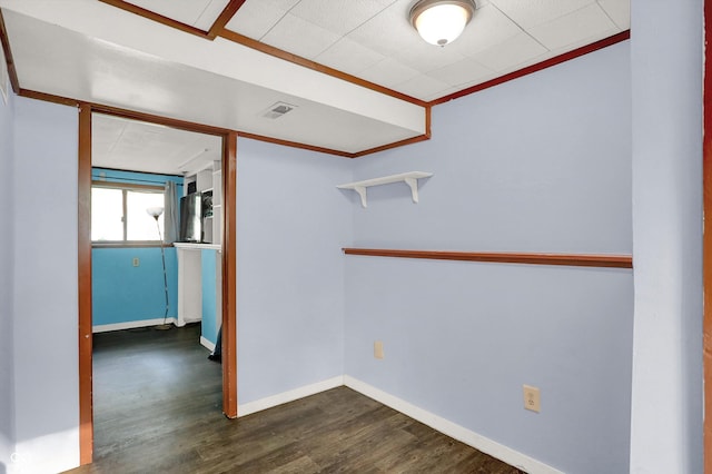 empty room with visible vents, baseboards, ornamental molding, and dark wood finished floors