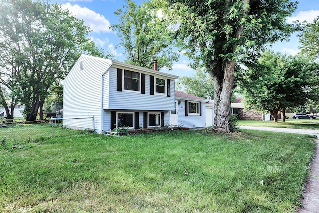 split level home with a front lawn and fence