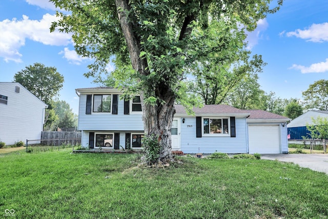 tri-level home with driveway, a front yard, and fence