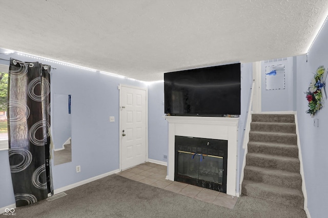 unfurnished living room featuring a fireplace with flush hearth, a textured ceiling, tile patterned flooring, carpet floors, and stairway