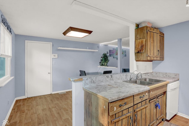 kitchen featuring light countertops, light wood-type flooring, a sink, and white dishwasher