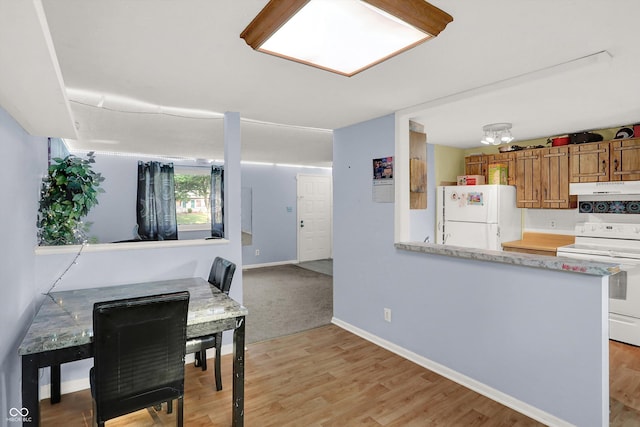 kitchen featuring white appliances, light countertops, under cabinet range hood, light wood-style floors, and brown cabinets