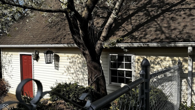 view of property exterior with a shingled roof and fence