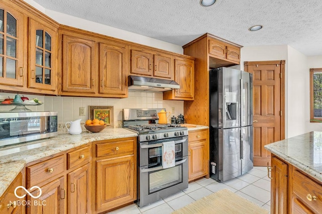 7113 Lakeside Woods Dr, Indianapolis, IN 46278 - kitchen with appliances with stainless steel finishes, under cabinet range hood, glass insert cabinets, backsplash, and light stone counters